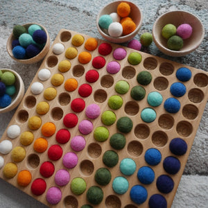 Hunderterbrett mit bunten Filzkugeln und Schüsseln