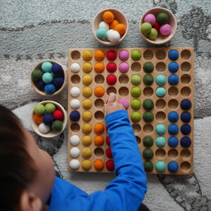 Kind spielt mit dem Hunderterbrett mit bunten Filzkugeln